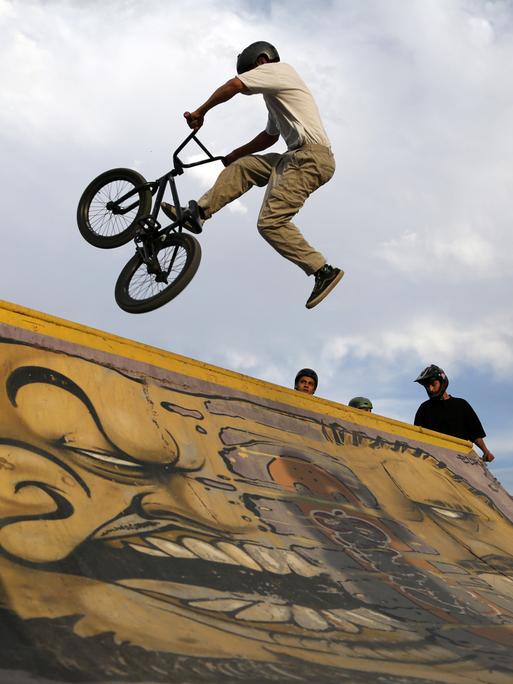 Jugendliche trainieren mit ihren BMX-Rädern an einer Rampe.