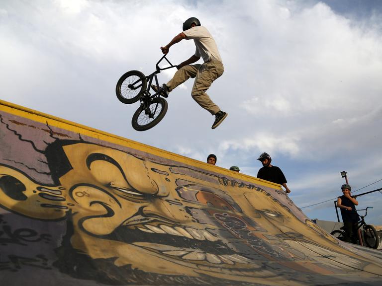 Jugendliche trainieren mit ihren BMX-Rädern an einer Rampe.