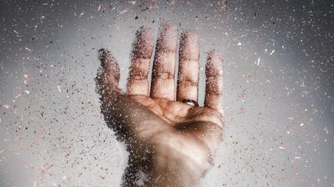 Nahaufnahme einer menschlichen Hand, die sich auflöst.