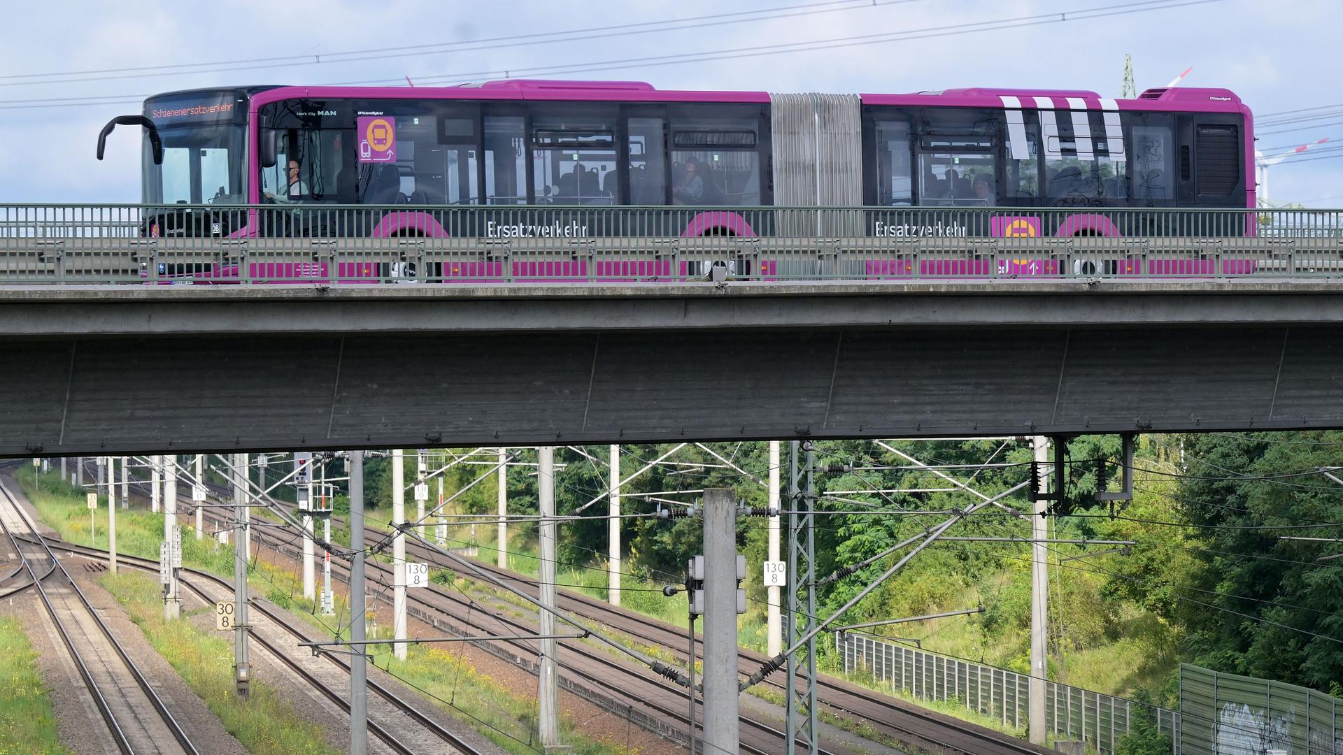 Ein Bus fährt über eine Brücke. Darunter sind Bahngleise.