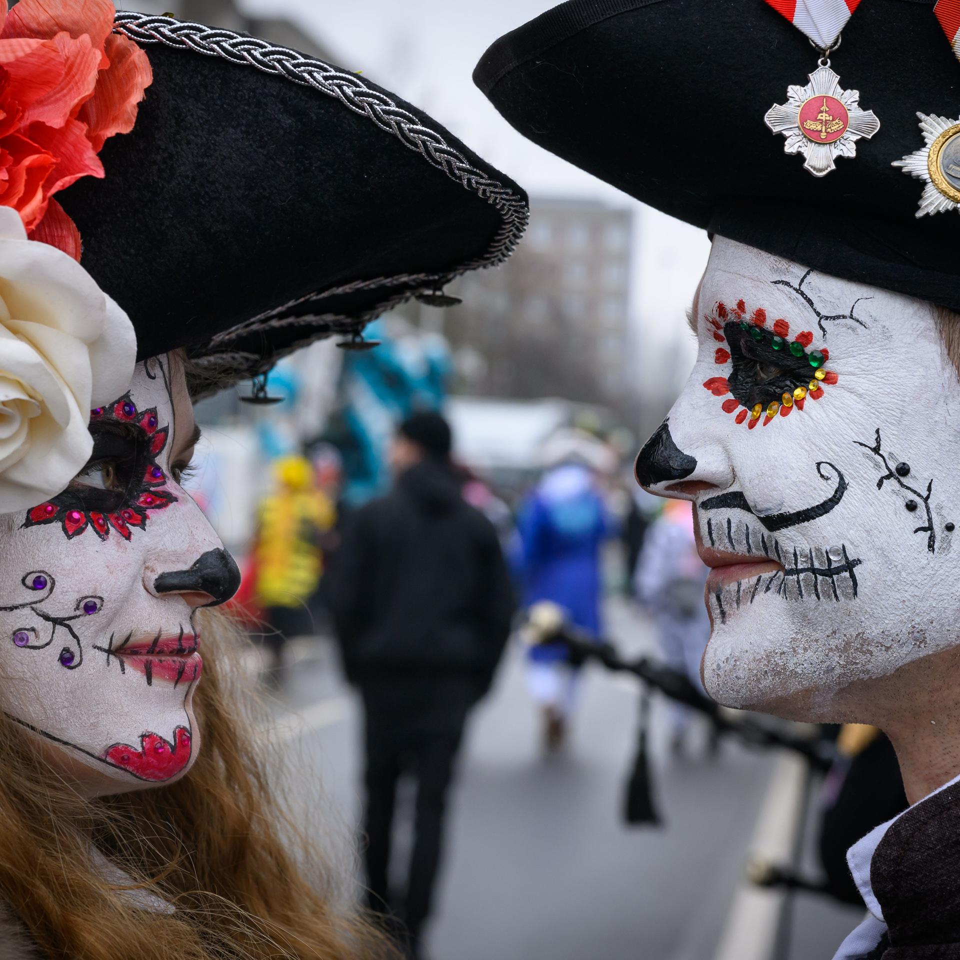 Zwei Teilnehmer am Karnevalsumzug "Zug der fröhlichen Leute" schauen sich in die Augen. Im Hintergrund zieht Teilnehmer durch die Straßen von Cottbus.