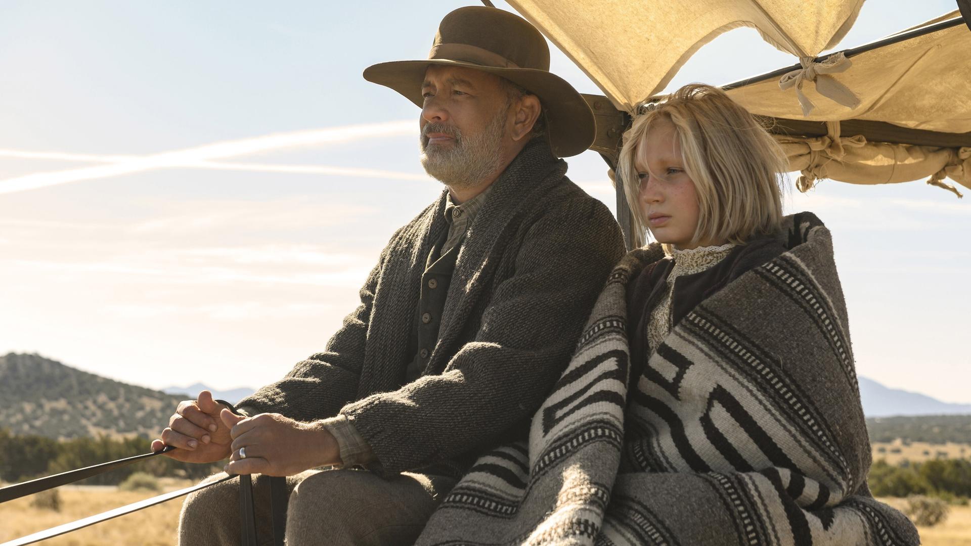Tom Hanks und Helena Zengel fahren in dem Film "News of the World" in einem Planwagen. © Universal Pictures / Courtesy Everett Collection Tom Hanks und Helena Zengel fahren in dem Film "News of the World" in einem Planwagen. © Universal Pictures / Courtesy Everett Collection