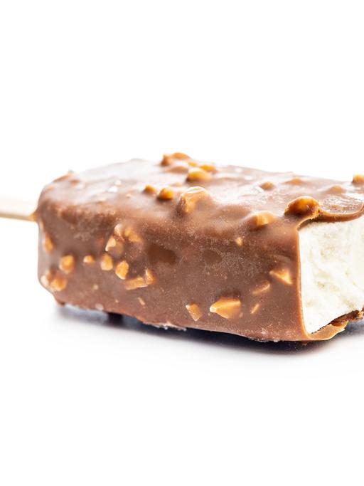 Eiscreme mit Schoko-Mandel-Umhüllung am Stiel, verführerisch vor weißem Hintergrund inszeniert: Am oberen Ende ist die Umhüllung bereits weg. 
