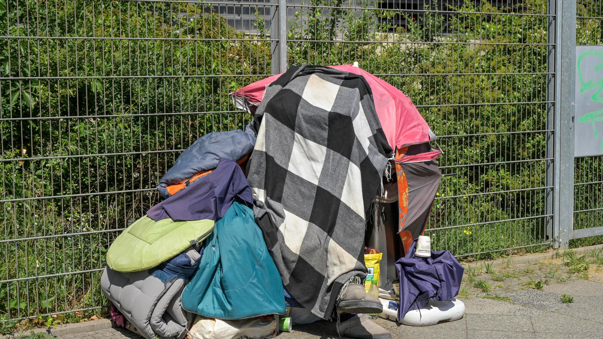 Eine wohnungslose Person in Berlin schützt sich gegen die Sonne mit Decken über dem Kopf. Eine wohnungslose Person in Berlin schützt sich gegen die Sonne mit Decken über dem Kopf.
