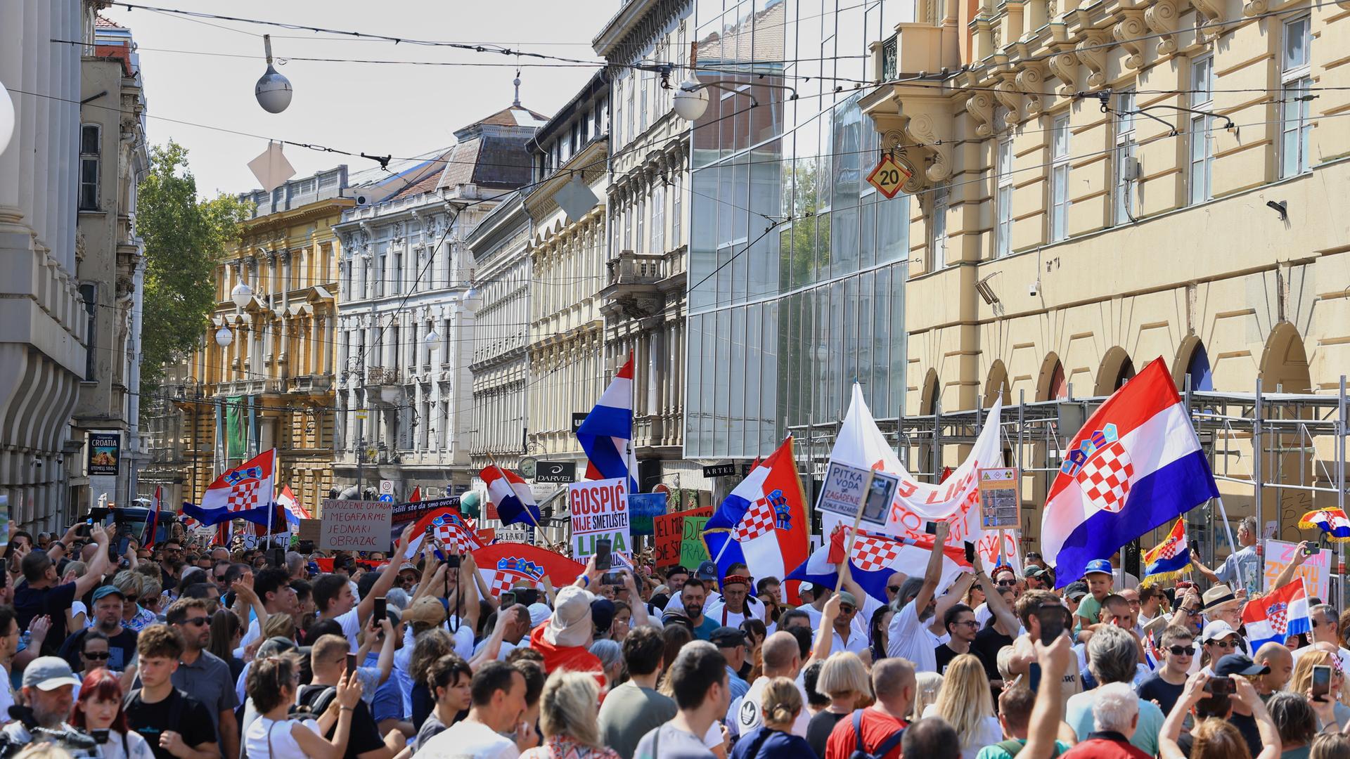 Ein große Menschengruppe steht in einer Straße mit alten Häusern und schwenkt kroatische Flaggen. Ein große Menschengruppe steht in einer Straße mit alten Häusern und schwenkt kroatische Flaggen.