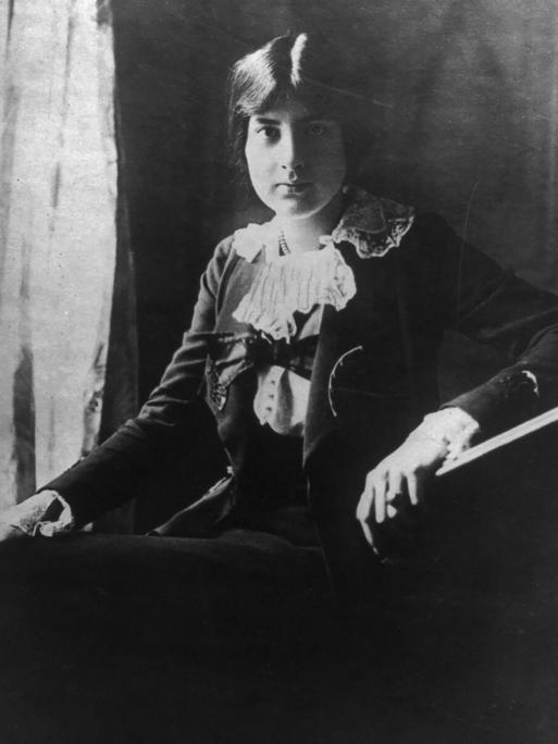Lili Boulanger sitzt mit ernstem Gesichtsausdruck und hochgesteckten Haaren vor der Kamera.