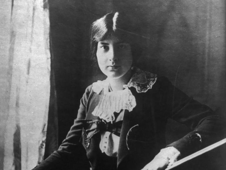 Lili Boulanger sitzt mit ernstem Gesichtsausdruck und hochgesteckten Haaren vor der Kamera.