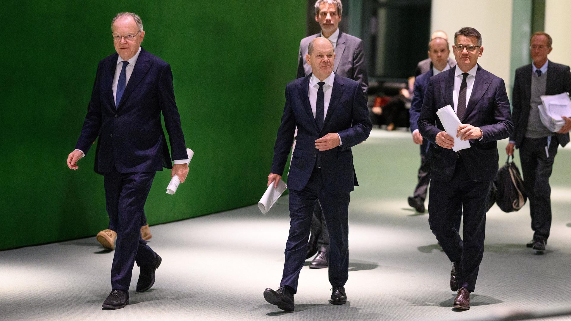 Bundeskanzler Olaf Scholz (M, SPD) kommt zusammen mit Boris Rhein (r, CDU), Ministerpräsident von Hessen, und Stephan Weil (l, SPD), Ministerpräsident von Niedersachsen, zu einer Pressekonferenz.