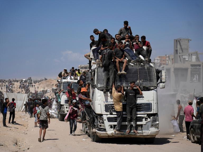 Menschen sitzen in Gaza auf einem Lkw, der Nahrungsmittel transportiert.