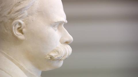 Eine weiße Büste von dem Philosophen Friedrich Nietzsche mit großem Schnurrbart steht im Treppenhaus. Sie ist im Profil zu sehen.