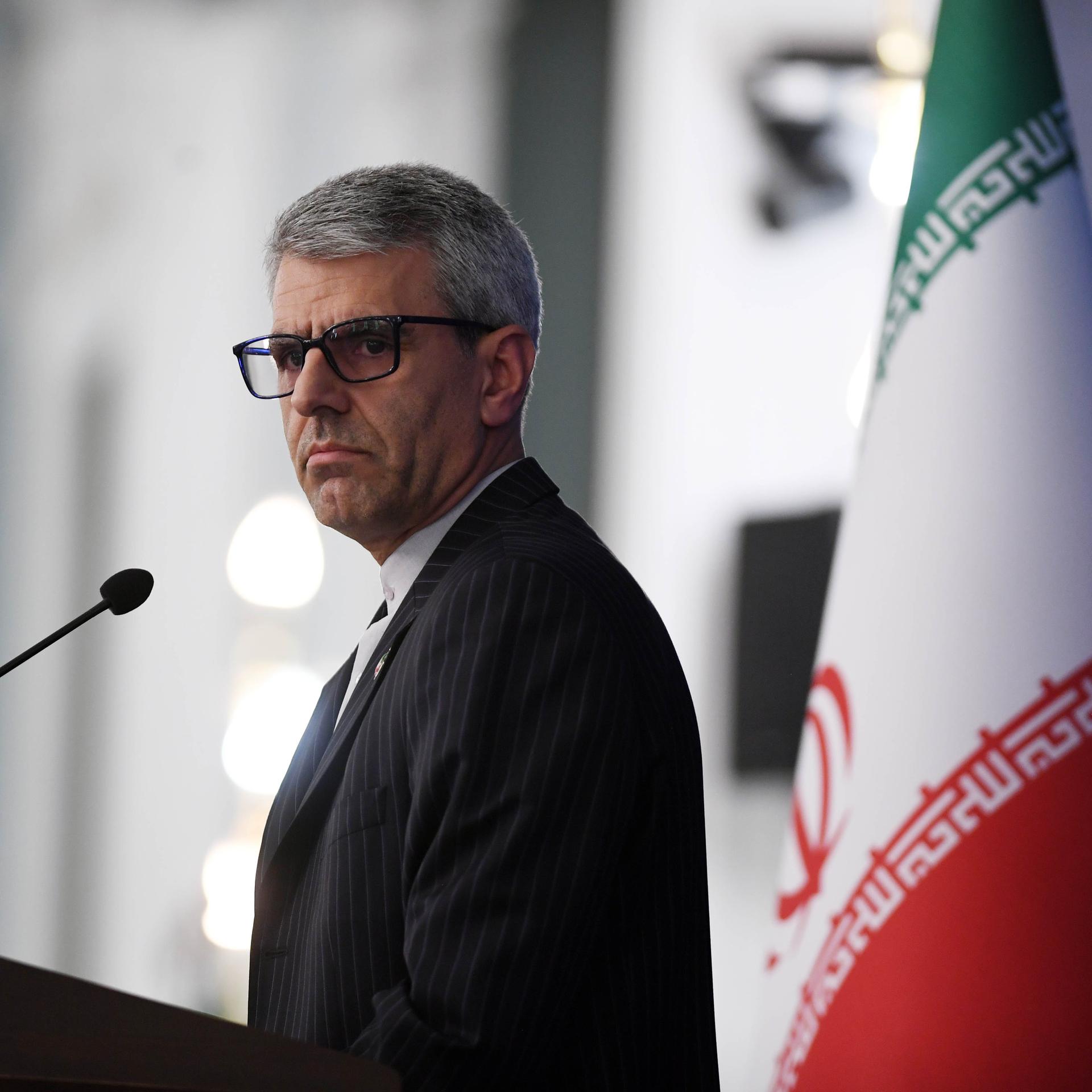 Ismail Baghai, Sprecher des iranischen Außenministeriums, schaut ernst. Neben ihm sind zwei große iranische Flaggen. 