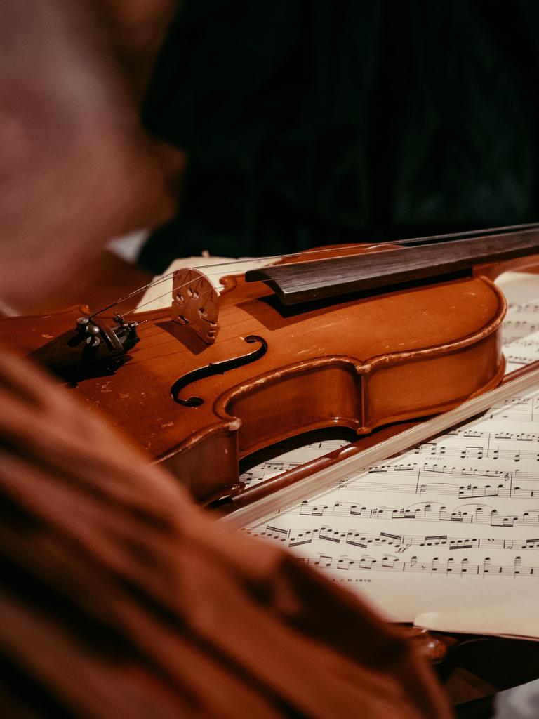Auf einem antiken Tisch liegen Notenblätter und eine Violine.