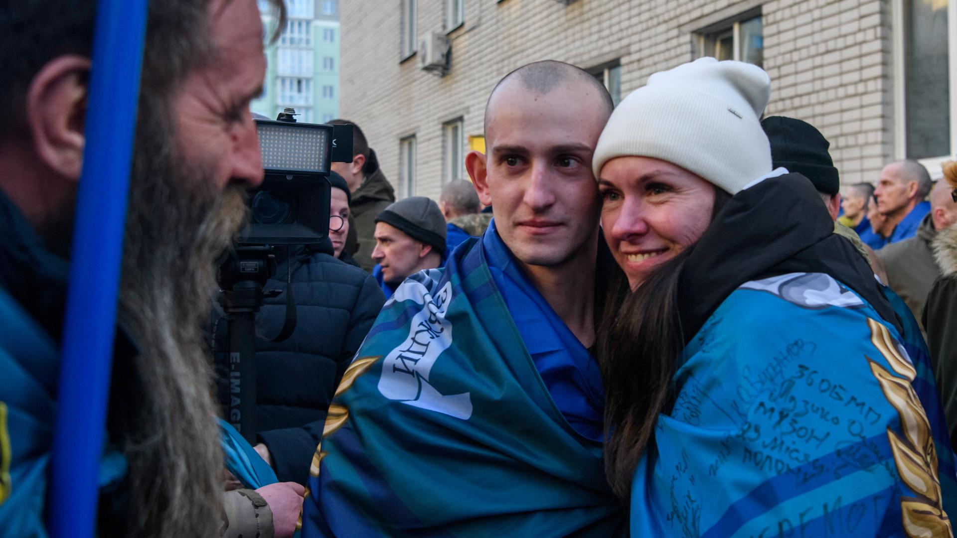 Ein Mann und eine Frau umarmen sich und blicken in die Kamera im Rahmen eines Gefangenenaustauschs zwischen Russland und Ukraine