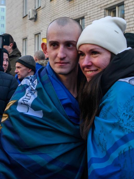 Ein Mann und eine Frau umarmen sich und blicken in die Kamera im Rahmen eines Gefangenenaustauschs zwischen Russland und Ukraine