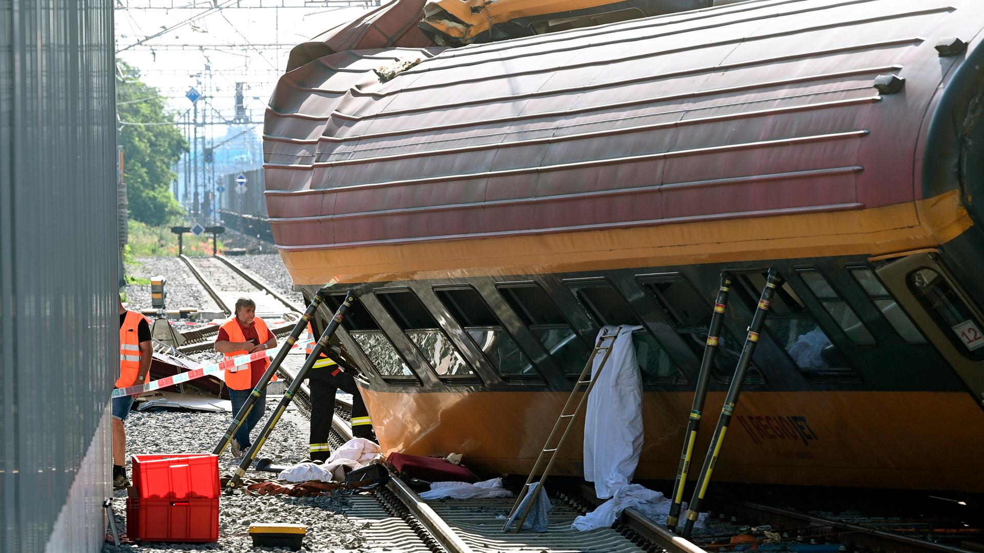 Rettungskräfte arbeiten an der Unfallstelle nach dem Zusammenstoß zweier Züge in Pardubice. Ein Personenzug ist in der Tschechischen Republik frontal mit einem Güterzug zusammengestoßen. Der Zug ist aus dem Gleis gesprungen und umgestürzt. Teile eines Waggons sind deformiert. Rettungskräfte arbeiten an der Unfallstelle nach dem Zusammenstoß zweier Züge in Pardubice. Ein Personenzug ist in der Tschechischen Republik frontal mit einem Güterzug zusammengestoßen. Der Zug ist aus dem Gleis gesprungen und umgestürzt. Teile eines Waggons sind deformiert.
