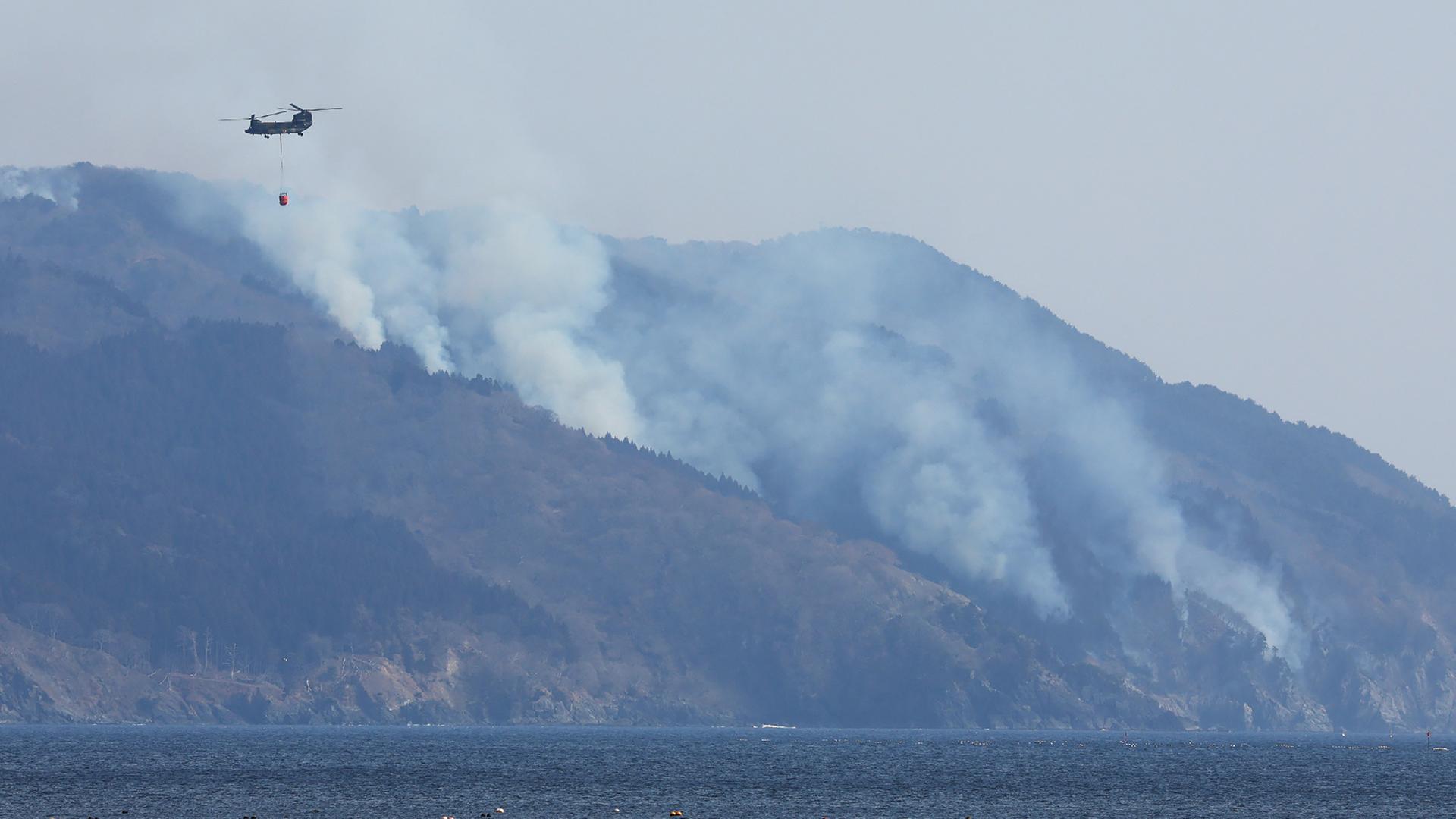 Das Foto zeigt einen Löschhubschrauber im Einsatz in der Nähe von Ofunato/Japan.