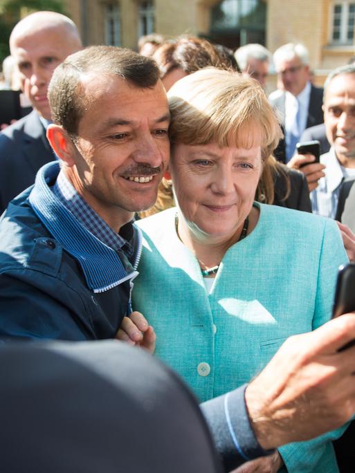Angela Merkel lässt sich am 10.09.2015 in Berlin-Spandau für ein Selfie zusammen mit einem Flüchtling fotografieren. 