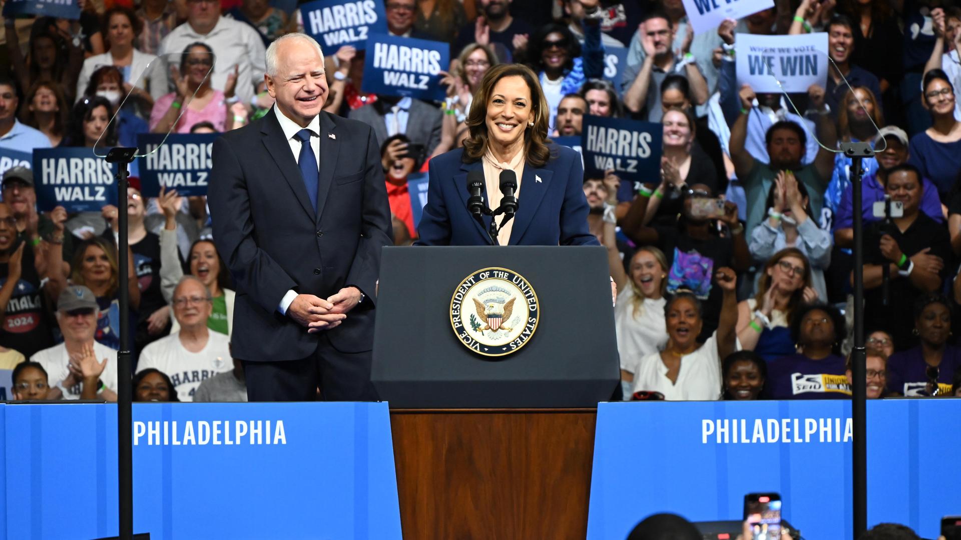 Kamala Harris steht mit Tim Walz an einem Rednerpult bei einer Wahlkampfveranstaltung in Philadelphia.