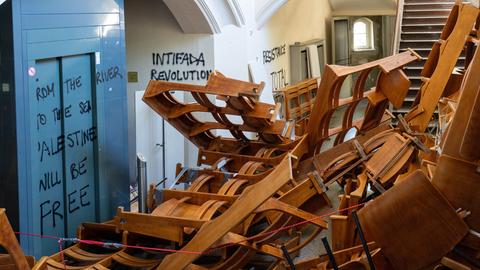 In einem Treppenflur der Humboldt-Universität zu Berlin stapeln sich herausgerissene Holzstuhlreihen vor dem Eingang eines Vorlesungssaals. Die Wände sind mit propalästinensischen und hamas-nahen Parolen beschmiert In einem Treppenflur der Humboldt-Universität zu Berlin stapeln sich herausgerissene Holzstuhlreihen vor dem Eingang eines Vorlesungssaals. Die Wände sind mit propalästinensischen und hamas-nahen Parolen beschmiert