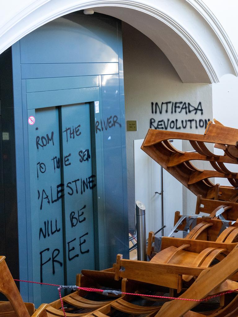 In einem Treppenflur der Humboldt-Universität zu Berlin stapeln sich herausgerissene Holzstuhlreihen vor dem Eingang eines Vorlesungssaals. Die Wände sind mit propalästinensischen und hamas-nahen Parolen beschmiert