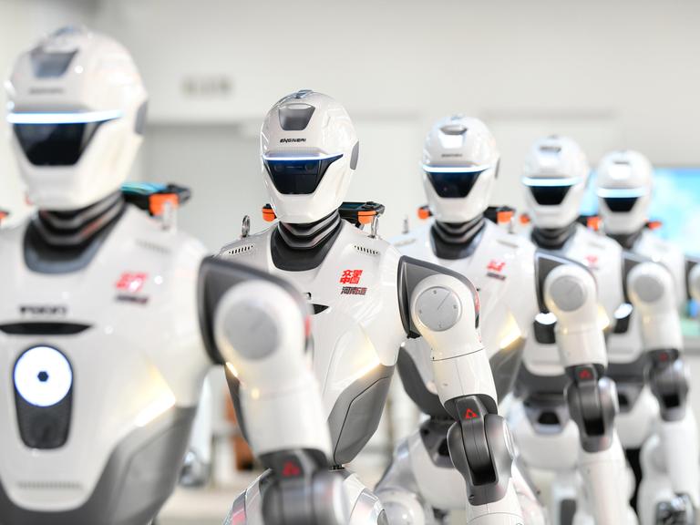 Mehrere humanoide Roboter der chinesischen Firma EngineAI stehen in einer Reihe.