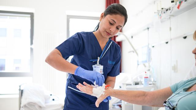 Eine indische Pflegekraft legt einer Patientin eine Infusion. 