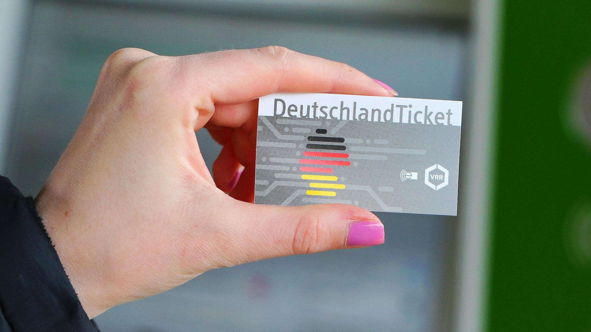 Eine Hand hält ein Deutschlandticket, das es ermöglicht für 49 Euro mit allen Verkehrsmitteln des öffentlchen Nachverkehrs zu reisen.