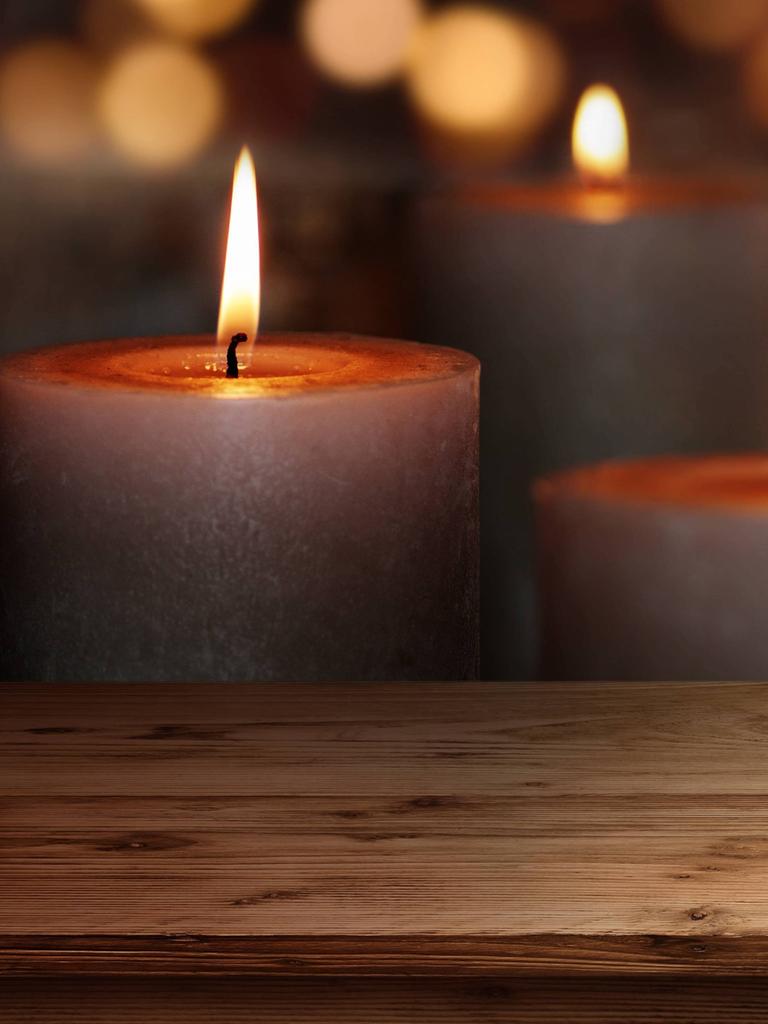Holztisch mit Kerzen vor dunklem Hintergrund