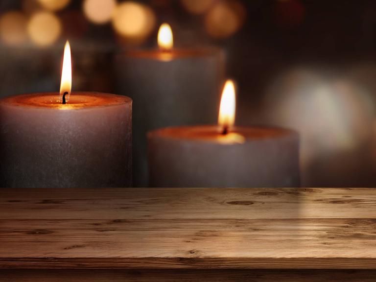 Holztisch mit Kerzen vor dunklem Hintergrund
