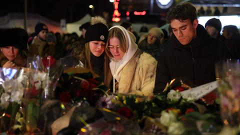 Zwei junge Mädchen trauern vor der Bar „Le Constellation" in Crans-Montana nach der Brandkatastrophe mit zahlreichen Toten und Verletzten am 1. Januar 2026