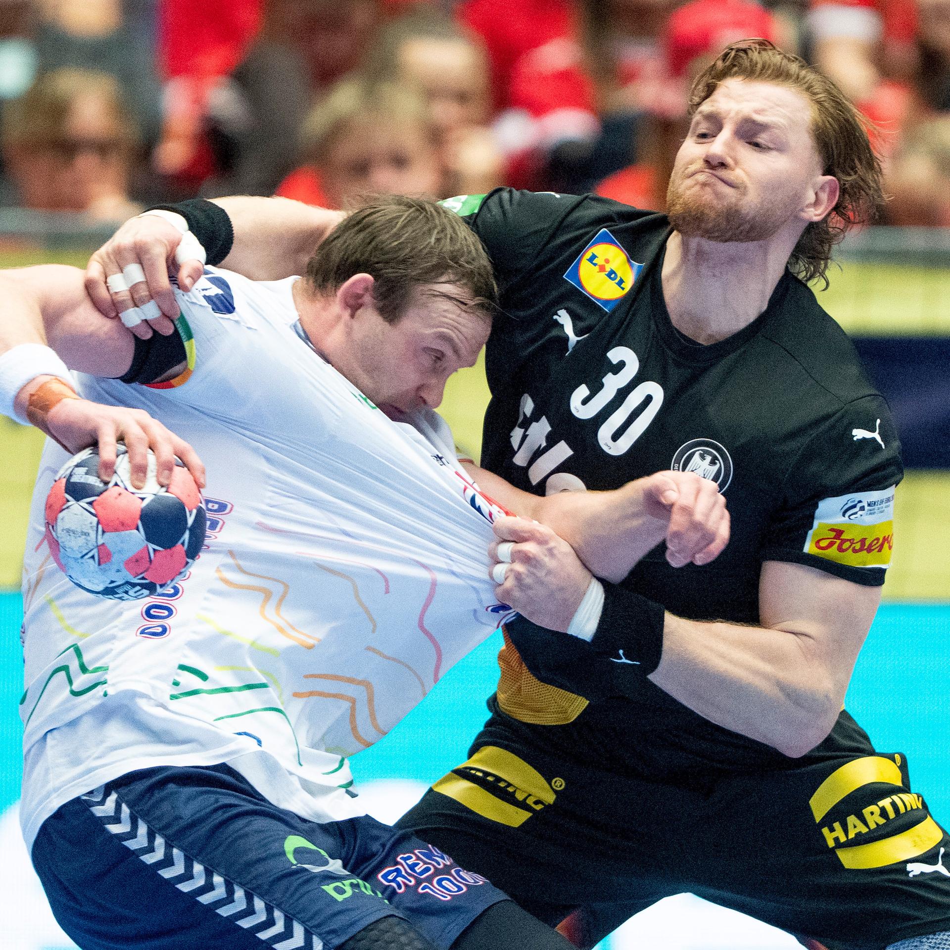 Der deutsche Spieler zieht dem norwegischen Spieler vorne am Trikot.