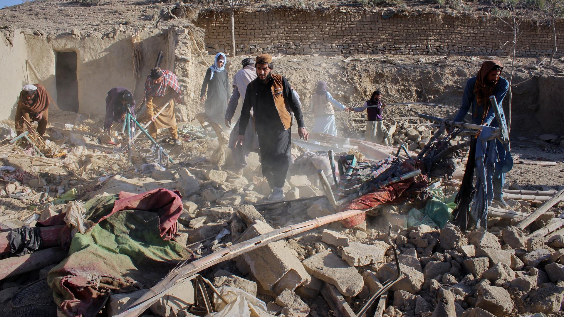 Afghanische Männer suchen in den Trümmern eines Hauses nach Opfern.