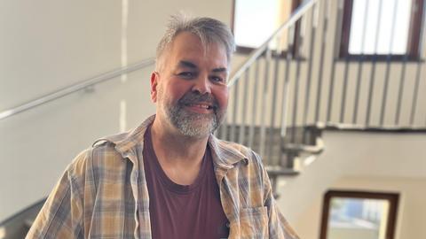 Claus Hempfling lächelt in die Kamera. Er hat einen kurzen, graumelierten Vollbart und trägt ein kariertes Hemd.