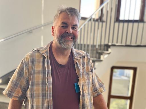 Claus Hempfling lächelt in die Kamera. Er hat einen kurzen, graumelierten Vollbart und trägt ein kariertes Hemd.
