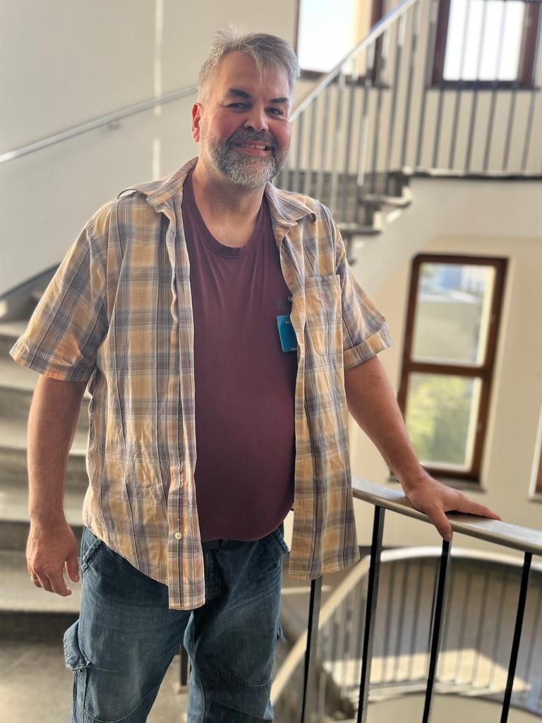 Claus Hempfling lächelt in die Kamera. Er hat einen kurzen, graumelierten Vollbart und trägt ein kariertes Hemd.