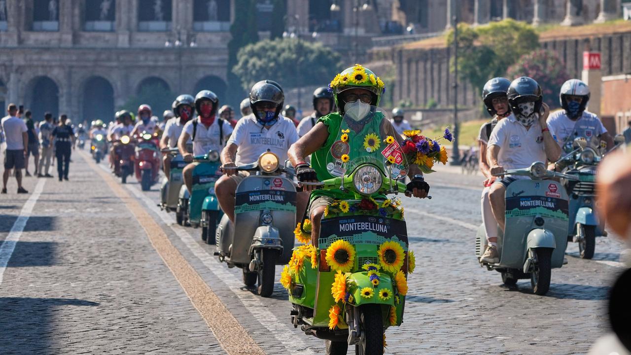 Vespa-Fans fahren anlässlich des 80-jährigen Jubiläums mit ihren Motorrollern in Rom am Kolosseum vorbei. 