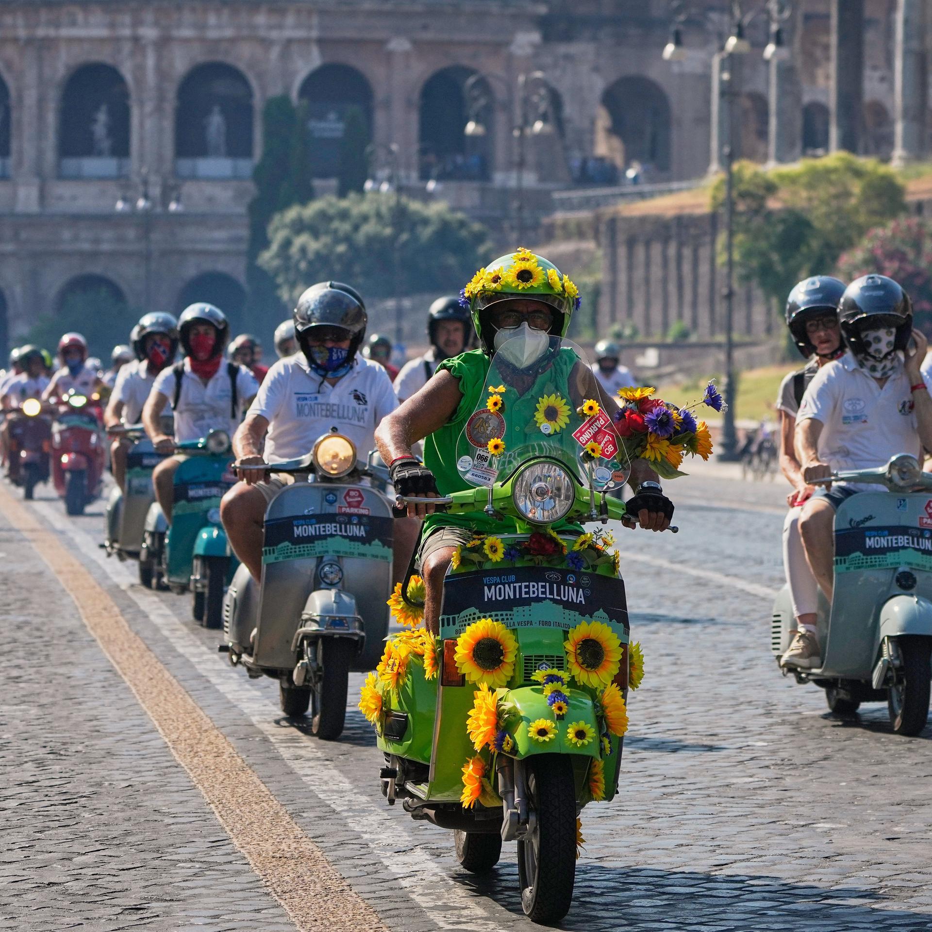 Vespa-Fans fahren anlässlich des 80-jährigen Jubiläums mit ihren Motorrollern in Rom am Kolosseum vorbei. 