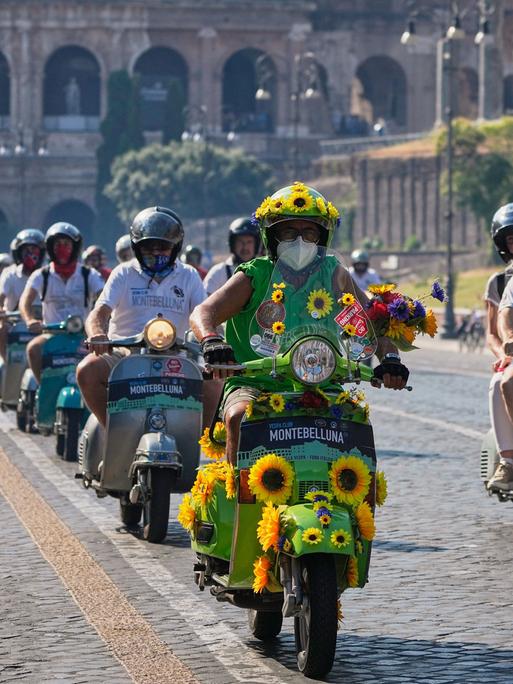 Vespa-Fans fahren anlässlich des 80-jährigen Jubiläums mit ihren Motorrollern in Rom am Kolosseum vorbei. 