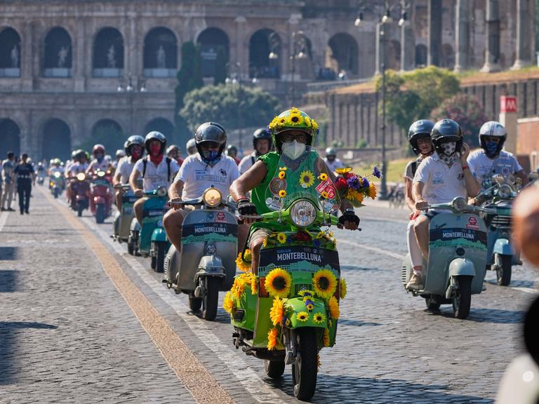 Vespa-Fans fahren anlässlich des 80-jährigen Jubiläums mit ihren Motorrollern in Rom am Kolosseum vorbei. 