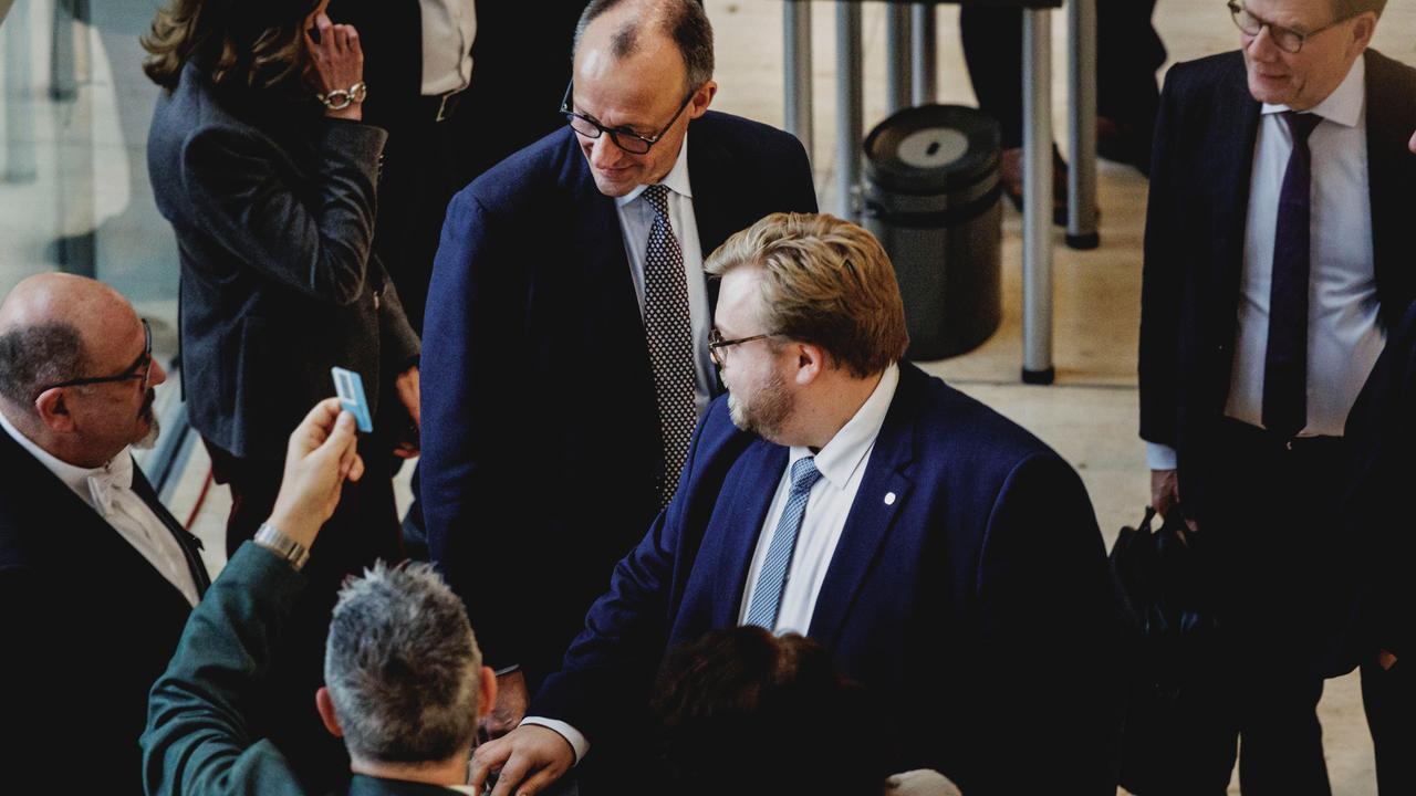 Blick in die Abstimmung über das Rentenpaket im Deutschen Bundestag in Berlin, zu sehen sind mehrere Abgeordnete sowie Bundeskanzler Merz. Einer der Abgeordneten hält eine Stimmkarte in die Höhe.