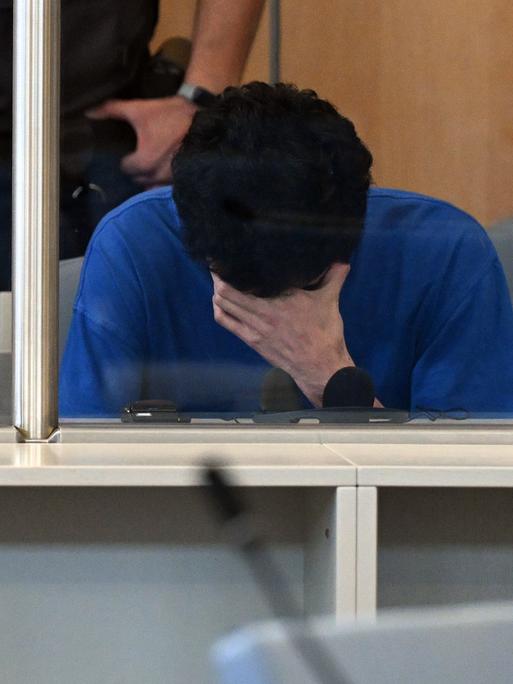 Der Angeklagte im Gerichtssaal der Oberlandesgerichts mit gesenktem Kopf und einer Hand vor dem Gesicht