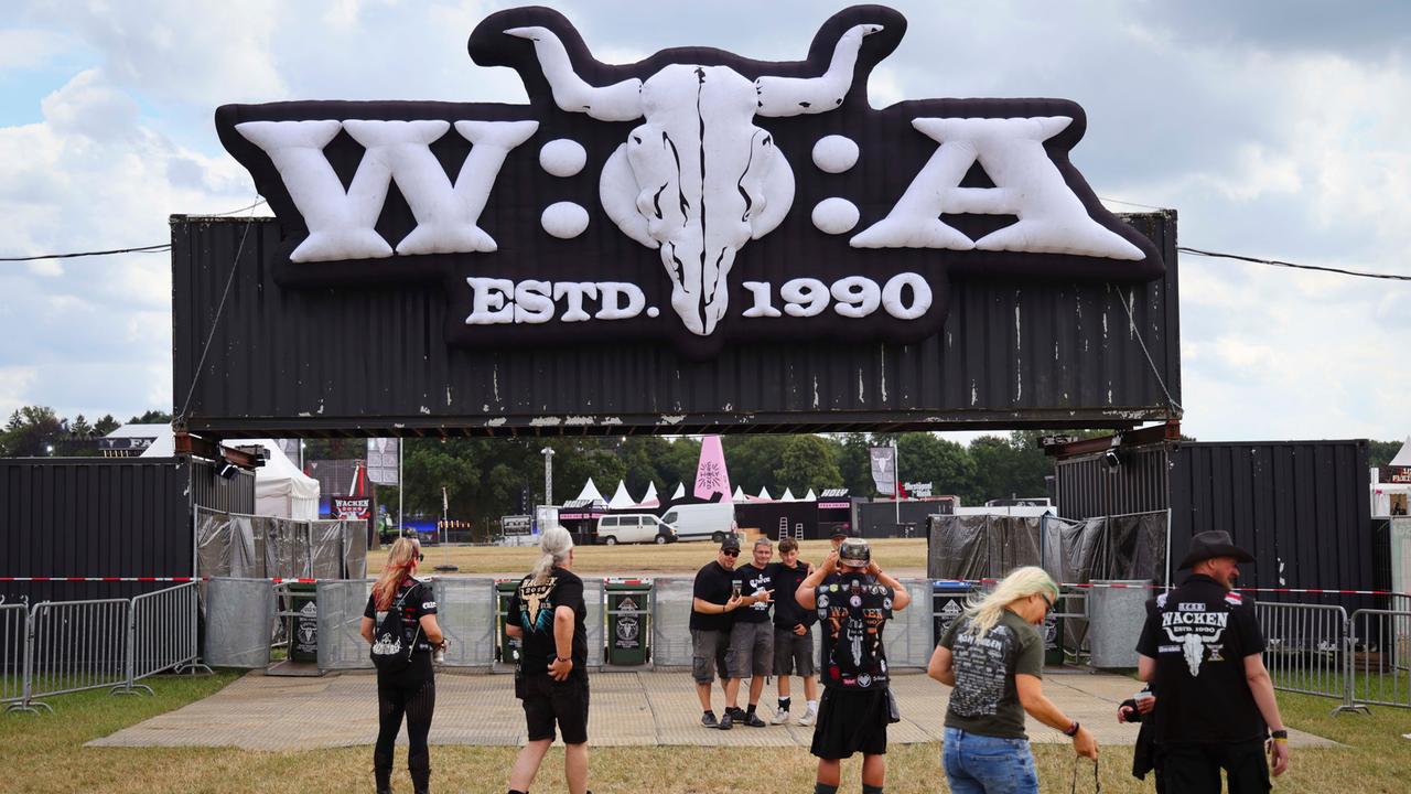 Festivalbesucher fotografieren sich vor dem Logo des Wacken Open Air (W:O:A). 