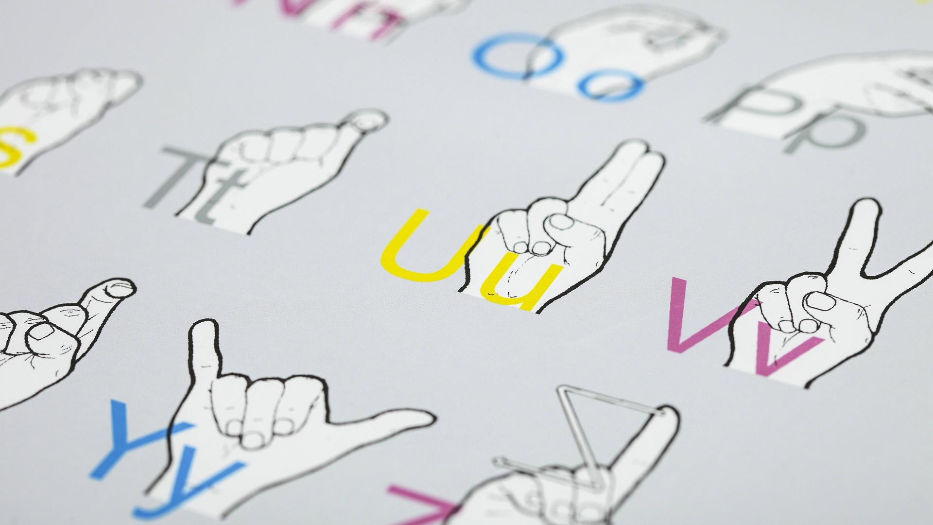 Eine Tafel zum Lernen der Gebärdensprache zeigt bunte Buchstaben und die dazugehörigen Handzeichen.