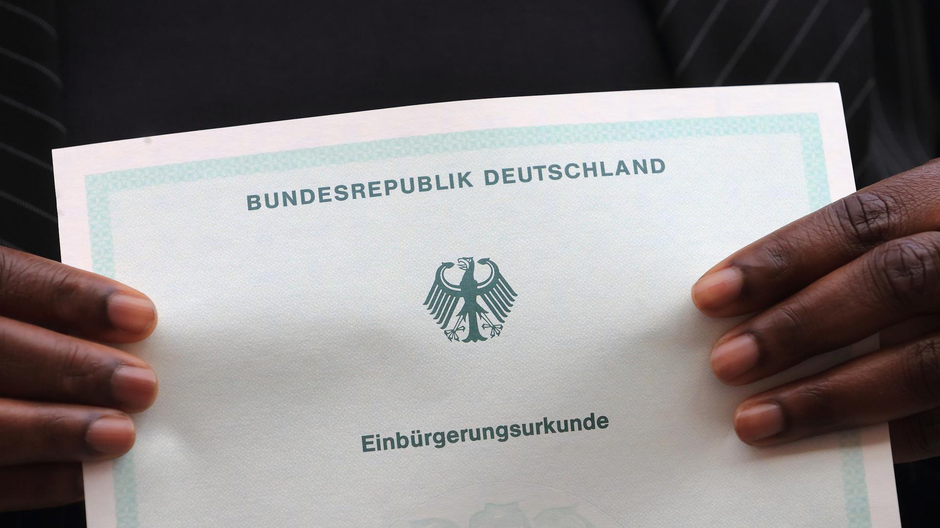 Eine in Afrika geborene Frau hält ihre Einbürgerungsurkunde der Bundesrepublik Deutschland in ihren Händen. Eine in Afrika geborene Frau hält ihre Einbürgerungsurkunde der Bundesrepublik Deutschland in ihren Händen.