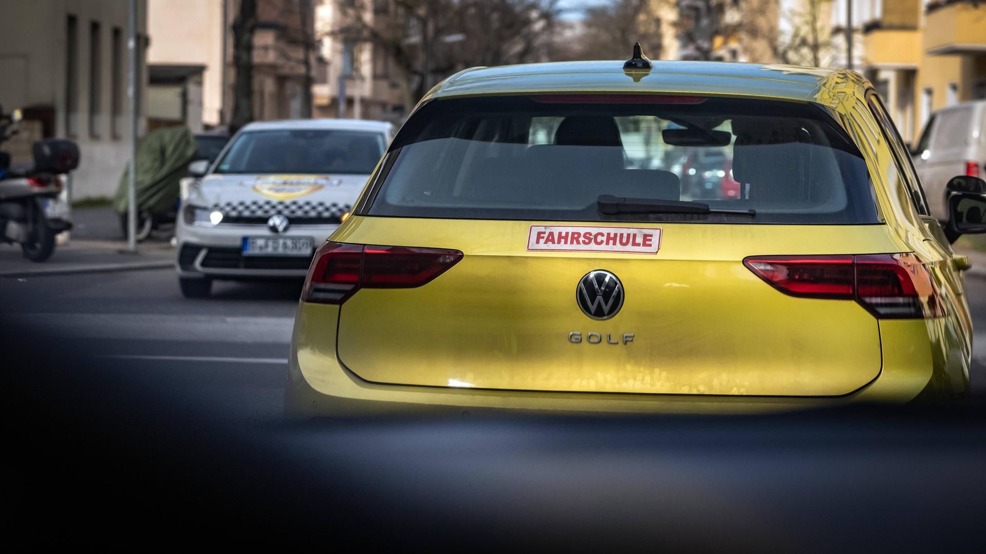 Blick durch die Frontscheibe eines PKW auf ein Auto mit der Aufschrift "Fahrschule" am Heck.