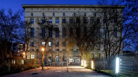 Der Eingangsbereich zum Club Berghain: ein rechteckiges Industriegebäude mit Fassade, unterbrochen von vertikalen Fensterflächen, davor mehrere Lampen zur Beleuchtung