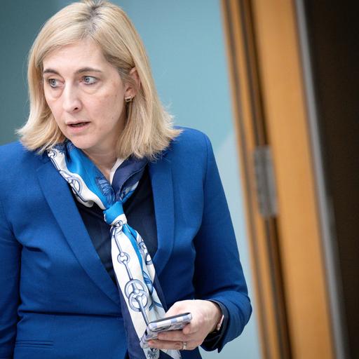 Bundesgesundheitsministerin Nina Warken hält ein Handy in ihrer linken Hand.