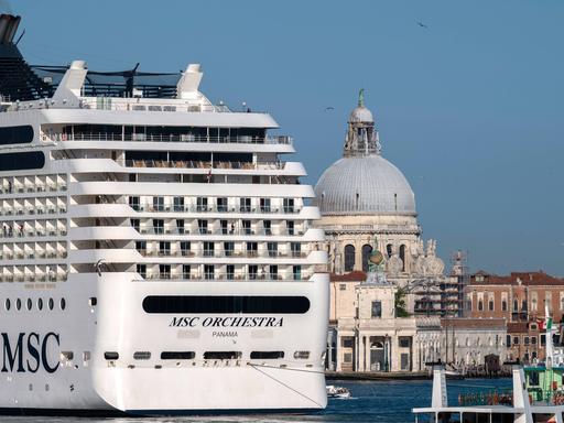 Ein großes Kreuzfahrtschiff fährt an Venedig vorbei. Die Stadt wirkt klein und fragil im Vergleich zu dem Luxusdampfer.