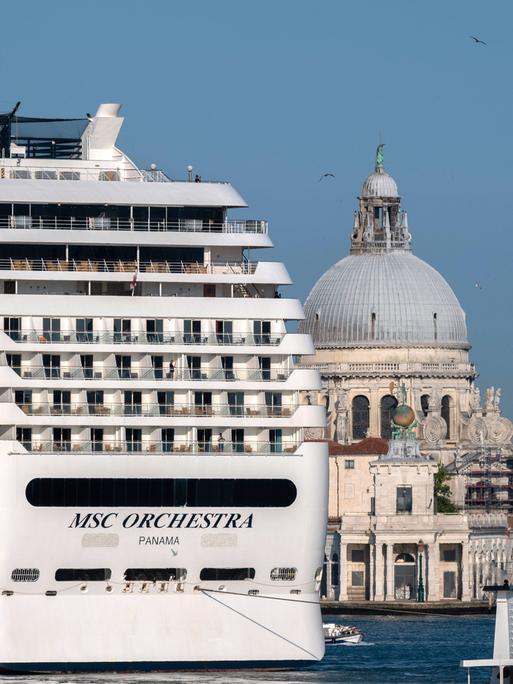 Ein großes Kreuzfahrtschiff fährt an Venedig vorbei. Die Stadt wirkt klein und fragil im Vergleich zu dem Luxusdampfer.