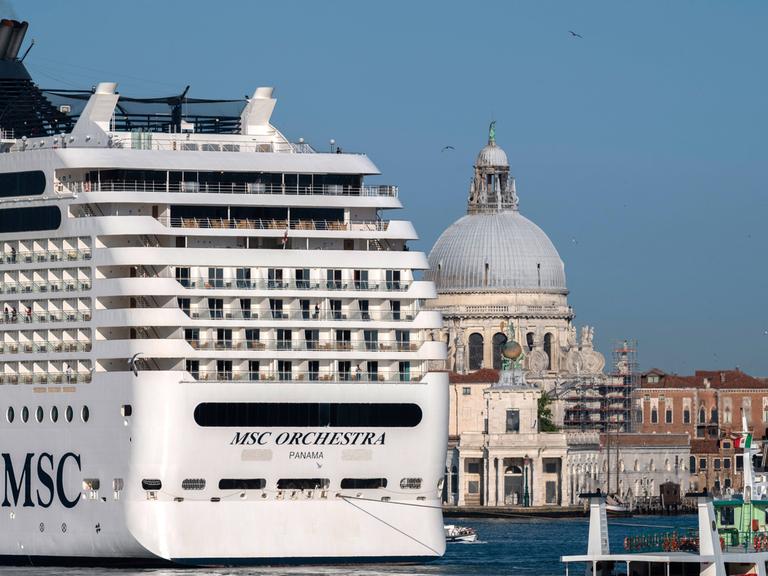 Ein großes Kreuzfahrtschiff fährt an Venedig vorbei. Die Stadt wirkt klein und fragil im Vergleich zu dem Luxusdampfer.